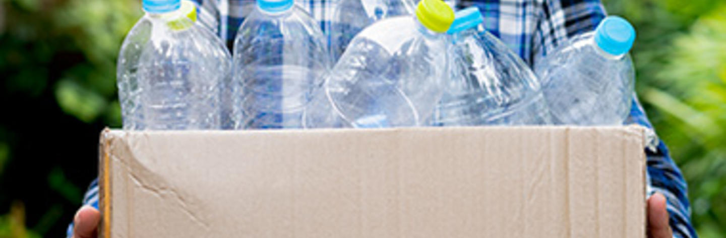 Mujer cargando botellas de plástico en caja cartón 
